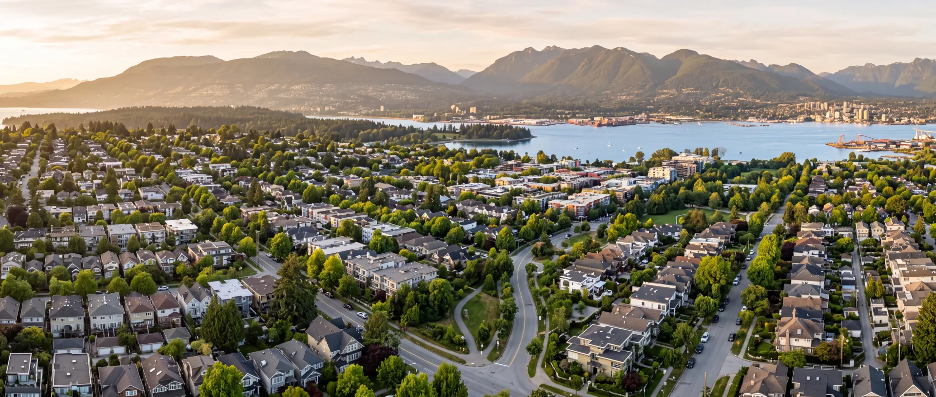 Aerial view of a Metro Vancouver residential neighbourhood with the North Shore mountains and Burrard Inlet at golden hour