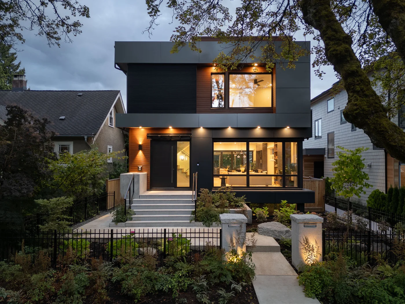 Modern black two-storey custom home lit at dusk, built by Venture Pacific in Vancouver