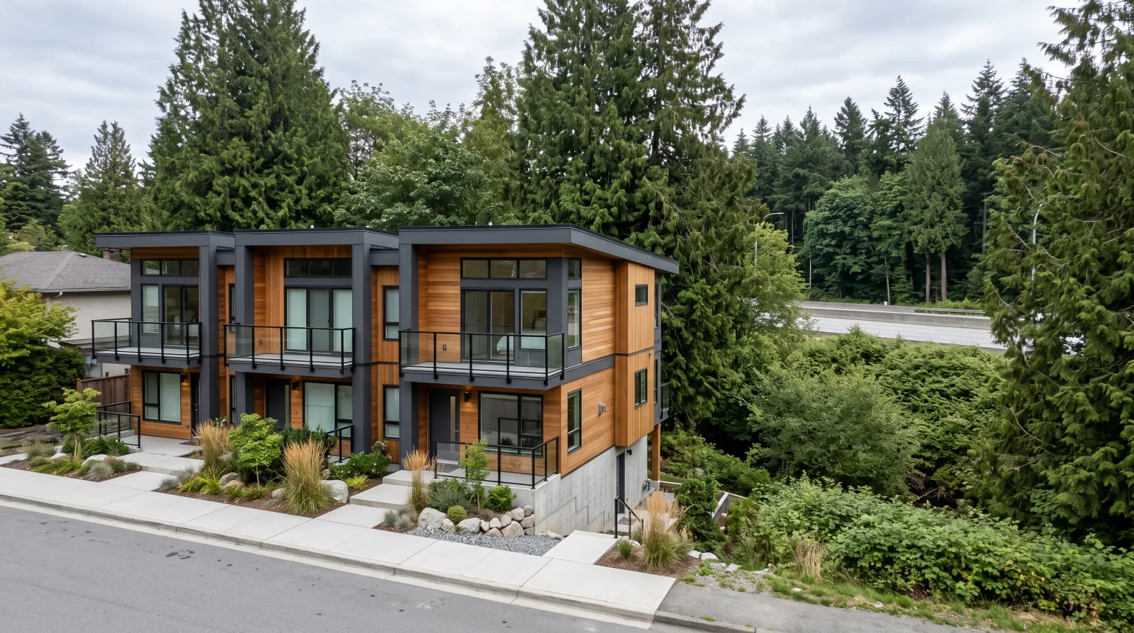 A small contemporary multiplex on a quiet street in Cedar Village, the eastern edge of the City of North Vancouver, framed by tall evergreens