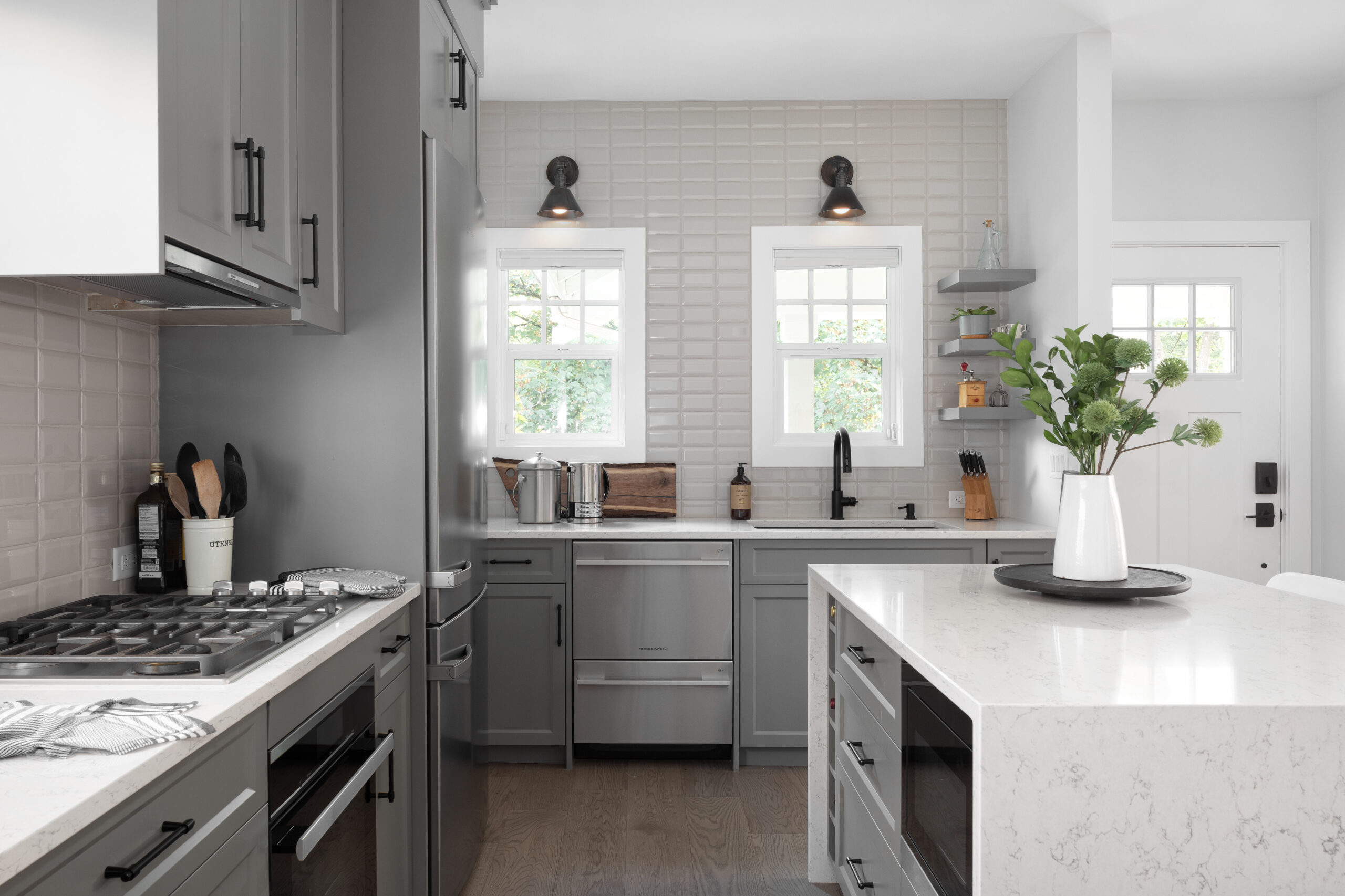 Renovated kitchen in Kitsilano with gray shaker cabinets, white quartz countertops, subway tile backsplash, and kitchen island